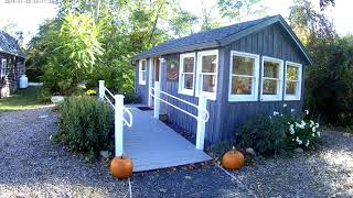 The restored blue cottage with windows, ramp, and garden